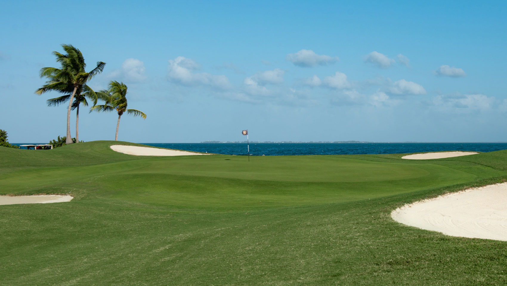 View of green with ocean in the distance