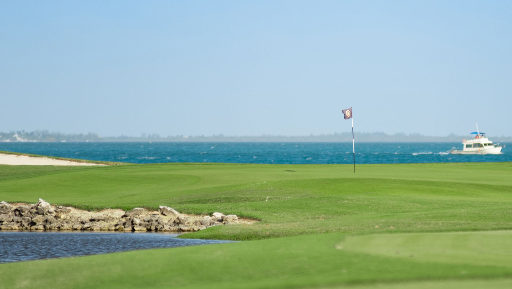 View of green with ocean and boat in the distance