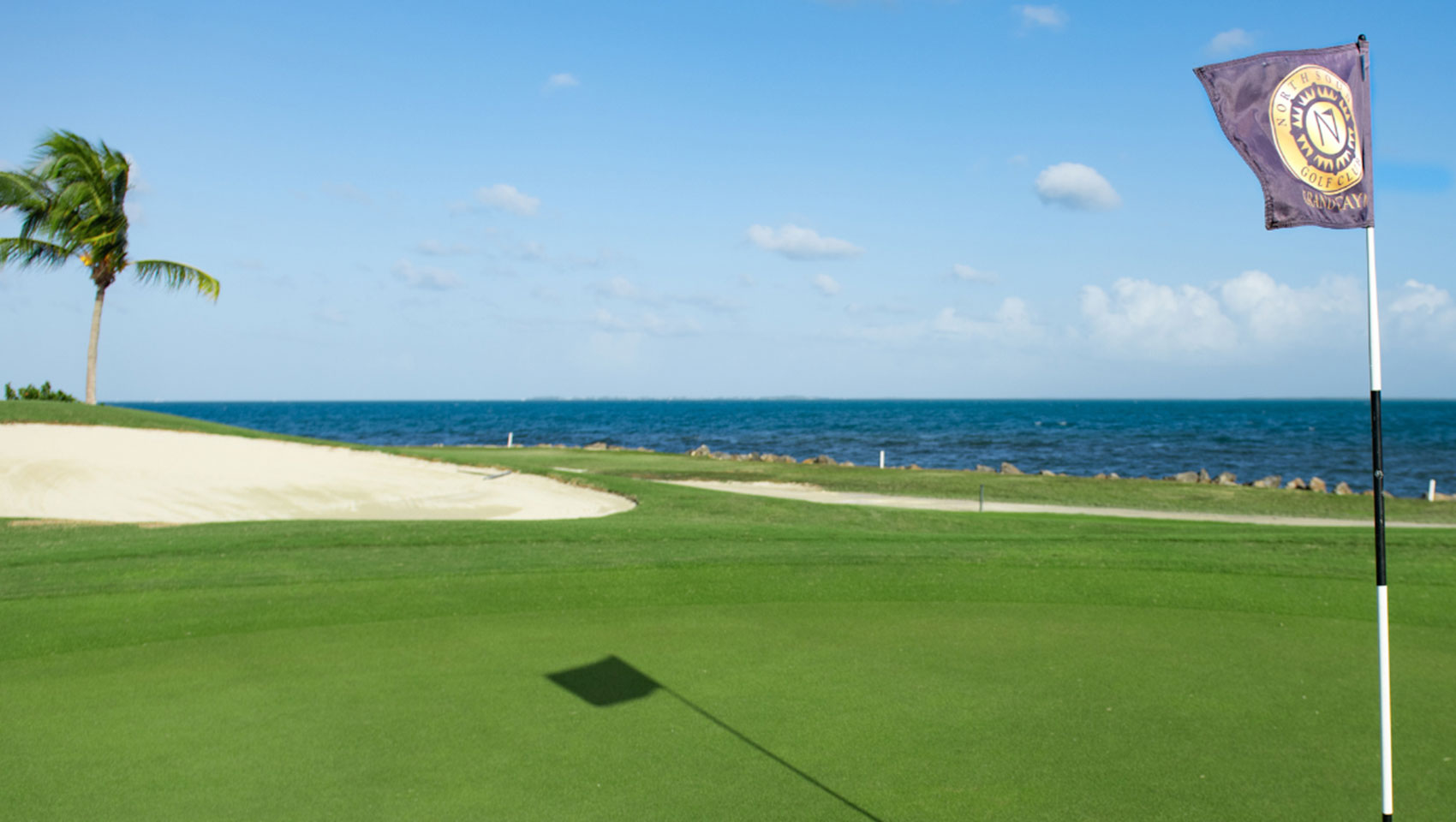 View of sand trap from the green with ocean in background