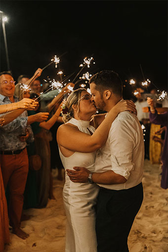 newlyweds kiss while wedding guests hold sparklers at Kimpton seafire